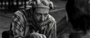 Movie still from “Adam Resurrected” (2008), directed by Paul Schrader – A black and white photo of a man wearing a hat; Close Up shot, High angle