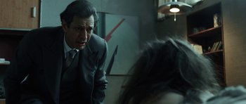 Movie still from “Adam Resurrected” (2008), directed by Paul Schrader – A man wearing a suit and tie in front of a woman; Medium shot, Over the shoulder angle