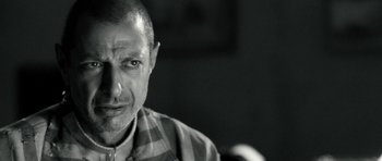Movie still from “Adam Resurrected” (2008), directed by Paul Schrader – Black and white photograph of a man in a checkered shirt; Close Up shot, Over the shoulder angle