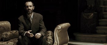 Movie still from “Adam Resurrected” (2008), directed by Paul Schrader – A man in a suit sitting on a chair; Medium shot, Low angle