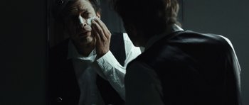 Movie still from “Adam Resurrected” (2008), directed by Paul Schrader – A man in a white dress shirt is looking in the mirror; Close Up shot, Over the shoulder angle