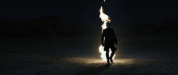 Movie still from “Adam Resurrected” (2008), directed by Paul Schrader – A man standing next to a fire at night; Wide shot, Low angle
