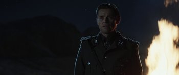 A man in a military uniform standing in the dark at night