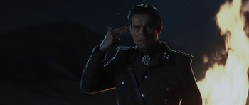 Movie still from “Adam Resurrected” (2008), directed by Paul Schrader – A man in a uniform saluting in the dark; Close Up shot, Over the shoulder angle
