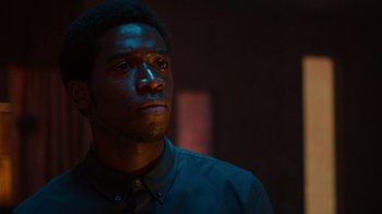 Movie still from “Snowfall” (2017), directed by Hiro Murai – A man in a black shirt is looking at the camera; Close Up shot, Low angle