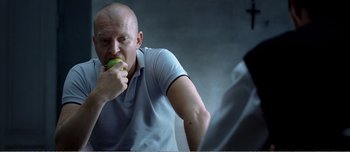 Movie still from “Adam's Apples” (2005), directed by Anders Thomas Jensen – A man eating an apple while sitting at a table; Close Up shot, Over the shoulder angle