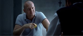 Movie still from “Adam's Apples” (2005), directed by Anders Thomas Jensen – A man holding an apple in front of a mirror; Close Up shot, Over the shoulder angle