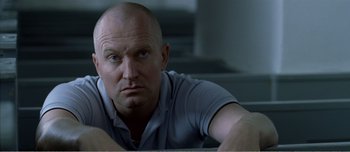 Movie still from “Adam's Apples” (2005), directed by Anders Thomas Jensen – A man with a bald head looking at the camera; Close Up shot, Low angle
