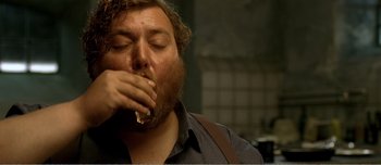 Movie still from “Adam's Apples” (2005), directed by Anders Thomas Jensen – A man with a beard is eating a piece of food; Close Up shot, High angle