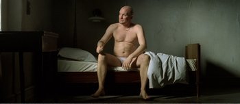 Movie still from “Adam's Apples” (2005), directed by Anders Thomas Jensen – A man sitting on a bed in his underwear; Medium shot, High angle