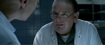 Movie still from “Adam's Apples” (2005), directed by Anders Thomas Jensen – An older man wearing glasses and a white lab coat; Close Up shot, Over the shoulder angle