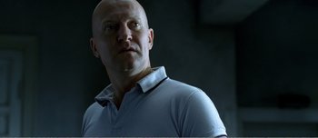 Movie still from “Adam's Apples” (2005), directed by Anders Thomas Jensen – A man with a bald head wearing a blue shirt; Close Up shot, Low angle