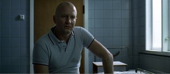Movie still from “Adam's Apples” (2005), directed by Anders Thomas Jensen – A bald man sitting at a table in front of a mirror; Close Up shot, Over the shoulder angle