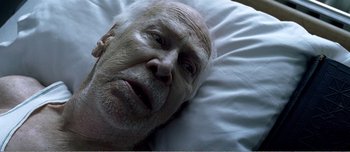Movie still from “Adam's Apples” (2005), directed by Anders Thomas Jensen – An older man laying in bed with a white blanket; Close Up shot, Overhead angle