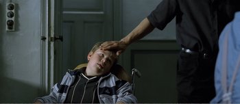 Movie still from “Adam's Apples” (2005), directed by Anders Thomas Jensen – A person touching the head of a child; Medium shot, Over the shoulder angle