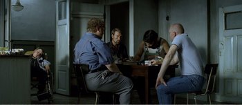 Movie still from “Adam's Apples” (2005), directed by Anders Thomas Jensen – A group of people sitting around a table; Medium shot, Over the shoulder angle