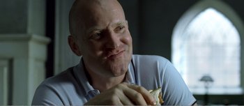 Movie still from “Adam's Apples” (2005), directed by Anders Thomas Jensen – A bald man with a shaved head eating a hot dog; Close Up shot, Over the shoulder angle