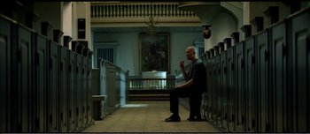 Movie still from “Adam's Apples” (2005), directed by Anders Thomas Jensen – A man sitting on a bench in front of a painting; Wide shot, Low angle
