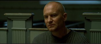 Movie still from “Adam's Apples” (2005), directed by Anders Thomas Jensen – A man with a bald head is sitting in a room; Close Up shot, Low angle