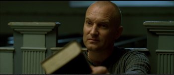 Movie still from “Adam's Apples” (2005), directed by Anders Thomas Jensen – A bald man with a book in his hands; Close Up shot, Low angle