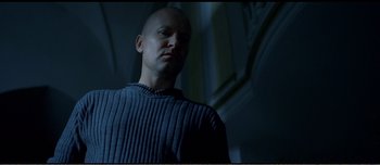 Movie still from “Adam's Apples” (2005), directed by Anders Thomas Jensen – A bald man in a blue sweater looking at the camera; Medium shot, Low angle