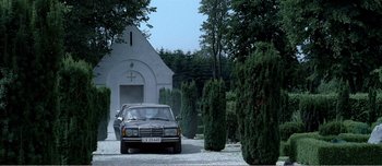 Movie still from “Adam's Apples” (2005), directed by Anders Thomas Jensen – A car is parked in front of a church; Extreme Wide shot, Low angle