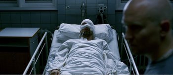 Movie still from “Adam's Apples” (2005), directed by Anders Thomas Jensen – A man with a bandaged head lying in a hospital bed; Medium shot, Overhead angle