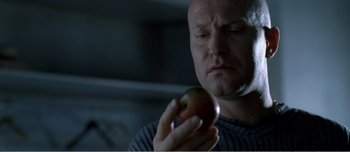 Movie still from “Adam's Apples” (2005), directed by Anders Thomas Jensen – A man holding an apple in front of his face; Close Up shot, Over the shoulder angle