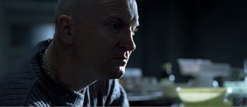 Movie still from “Adam's Apples” (2005), directed by Anders Thomas Jensen – A man with a bald head looking into the distance; Close Up shot, Over the shoulder angle