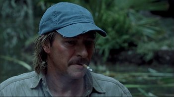 Movie still from “Adaptation.” (2002), directed by Spike Jonze – A person wearing a hat and smoking a cigarette; Close Up shot, Over the shoulder angle