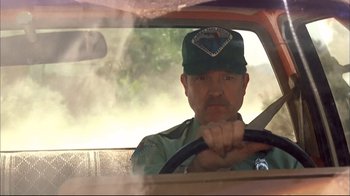 Movie still from “Adaptation.” (2002), directed by Spike Jonze – A man in a hat sitting in the drivers seat of a car; Medium shot, Low angle