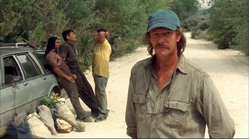 Movie still from “Adaptation.” (2002), directed by Spike Jonze – A group of men standing on a dirt road; Medium shot, Over the shoulder angle