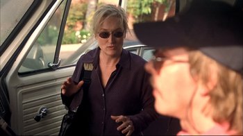 Movie still from “Adaptation.” (2002), directed by Spike Jonze – A woman holding a paintbrush while standing next to a car; Medium shot, Over the shoulder angle