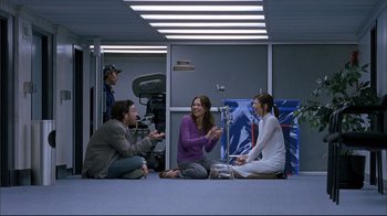 Movie still from “Adaptation.” (2002), directed by Spike Jonze – A group of people sitting on the ground in a room; Wide shot, Over the shoulder angle