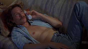 Movie still from “Adaptation.” (2002), directed by Spike Jonze – A man laying on a couch talking on a cell phone; Medium shot, High angle