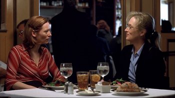 Movie still from “Adaptation.” (2002), directed by Spike Jonze – Two women sitting at a dinner table talking to each other; Medium shot, Over the shoulder angle