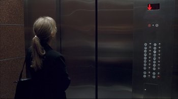 Movie still from “Adaptation.” (2002), directed by Spike Jonze – A woman standing in front of an elevator with her head turned to the side; Close Up shot, Over the shoulder angle