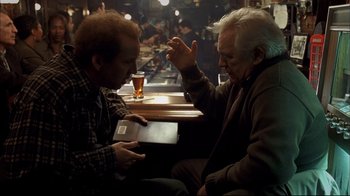 Movie still from “Adaptation.” (2002), directed by Spike Jonze – Two men sitting at a table in front of a glass of beer; Medium shot, Over the shoulder angle