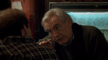 Movie still from “Adaptation.” (2002), directed by Spike Jonze – An older man smoking a cigarette in front of a television; Close Up shot, Over the shoulder angle