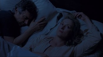 A man and a woman laying in a bed at night