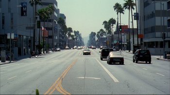 Movie still from “Adaptation.” (2002), directed by Spike Jonze – Cars driving down a street lined with palm trees; Extreme Wide shot, High angle