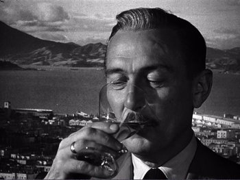 Movie still from “Address Unknown” (1944), directed by William Cameron Menzies – A black and white photo of a man drinking a glass of wine; Close Up shot, Low angle