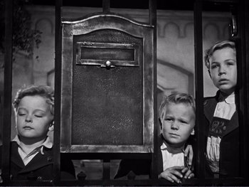 Movie still from “Address Unknown” (1944), directed by William Cameron Menzies – Three children standing next to each other in front of an open mailbox; Medium shot, Low angle