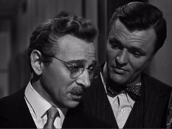 Movie still from “Address Unknown” (1944), directed by William Cameron Menzies – A man in a suit and tie next to another man in a suit and tie; Close Up shot, Over the shoulder angle