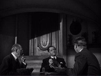 Movie still from “Address Unknown” (1944), directed by William Cameron Menzies – A group of men sitting around a table; Medium shot, Over the shoulder angle