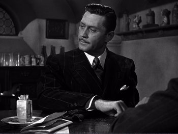 Movie still from “Address Unknown” (1944), directed by William Cameron Menzies – A man sitting at a table in front of a mirror; Close Up shot, Over the shoulder angle