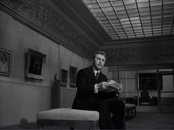 Movie still from “Address Unknown” (1944), directed by William Cameron Menzies – A black and white photo of a man sitting on a bench; Medium shot, Low angle