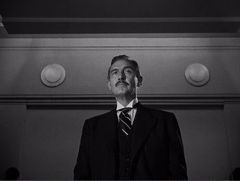 Movie still from “Address Unknown” (1944), directed by William Cameron Menzies – Black and white photograph of a man in a suit and tie; Close Up shot, Low angle