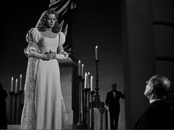 Movie still from “Address Unknown” (1944), directed by William Cameron Menzies – A man and a woman are standing in front of candles; Medium shot, Low angle