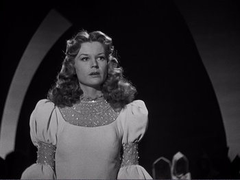 Movie still from “Address Unknown” (1944), directed by William Cameron Menzies – A black and white photo of a woman in a dress; Medium shot, Low angle